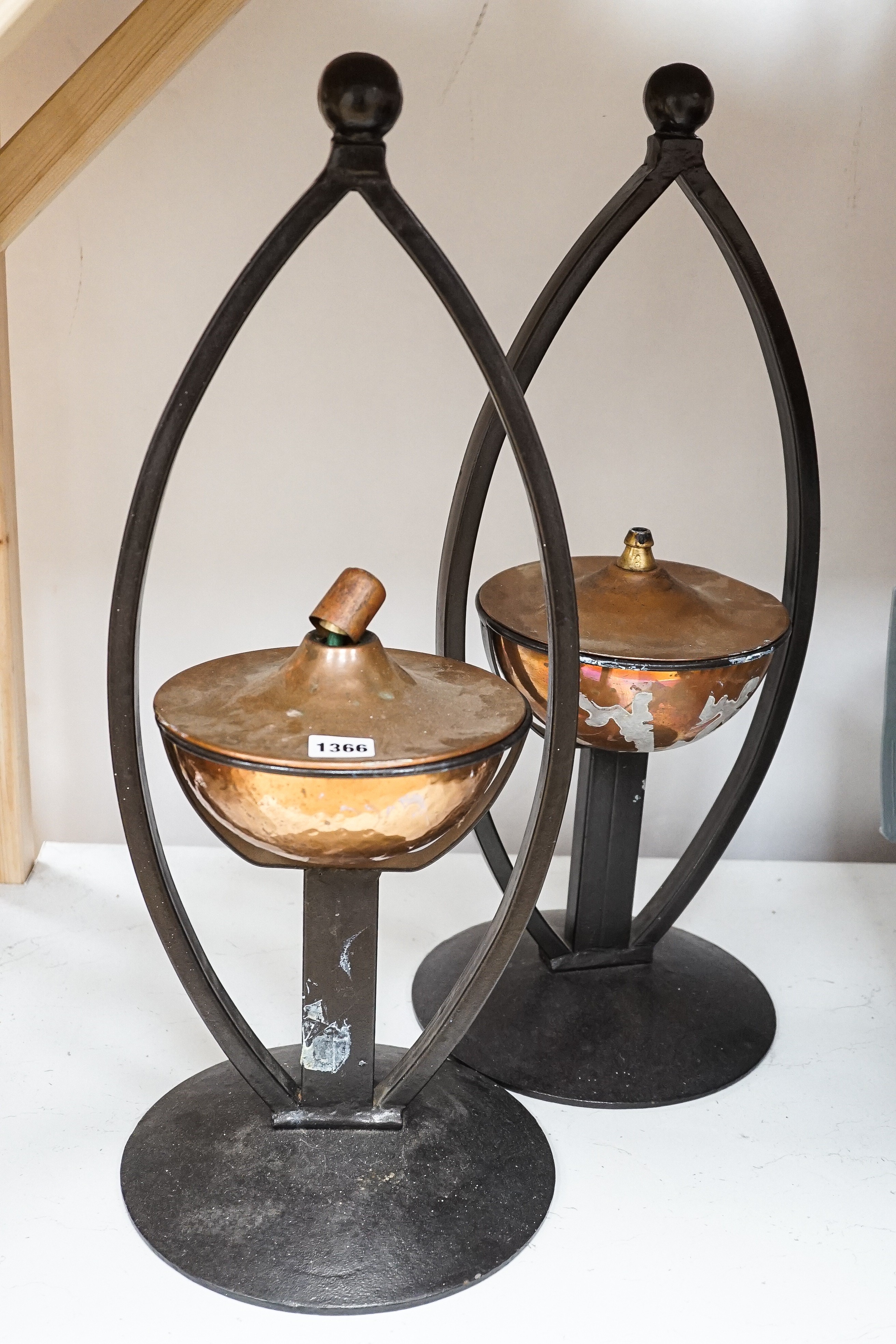 A pair of decorative copper lamps in arched mounts, 61 cms high.